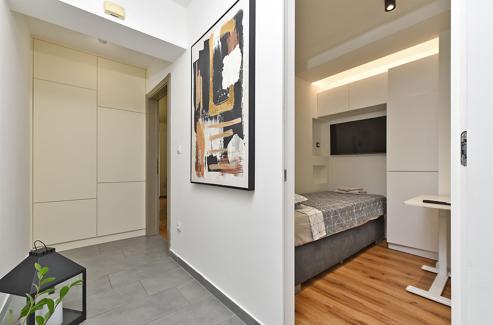 A modern bedroom with a bed, bedside table, and a TV.