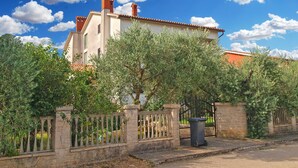 A villa with a stone fence, a garden, and a clear blue sky. - Apartment Milka 442 (Fazana)