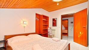 A bedroom with a wooden ceiling, a bed with a patterned bedspread, a nightstand, a wardrobe, and a mirror on the wall. - Apartment Milka 442 (Fazana)