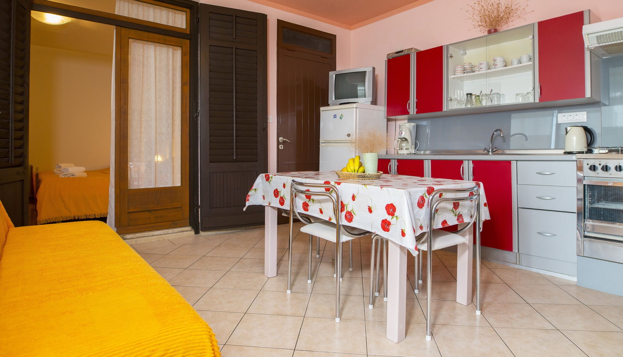 A compact hotel room with a bed, a small kitchenette, and a dining area.