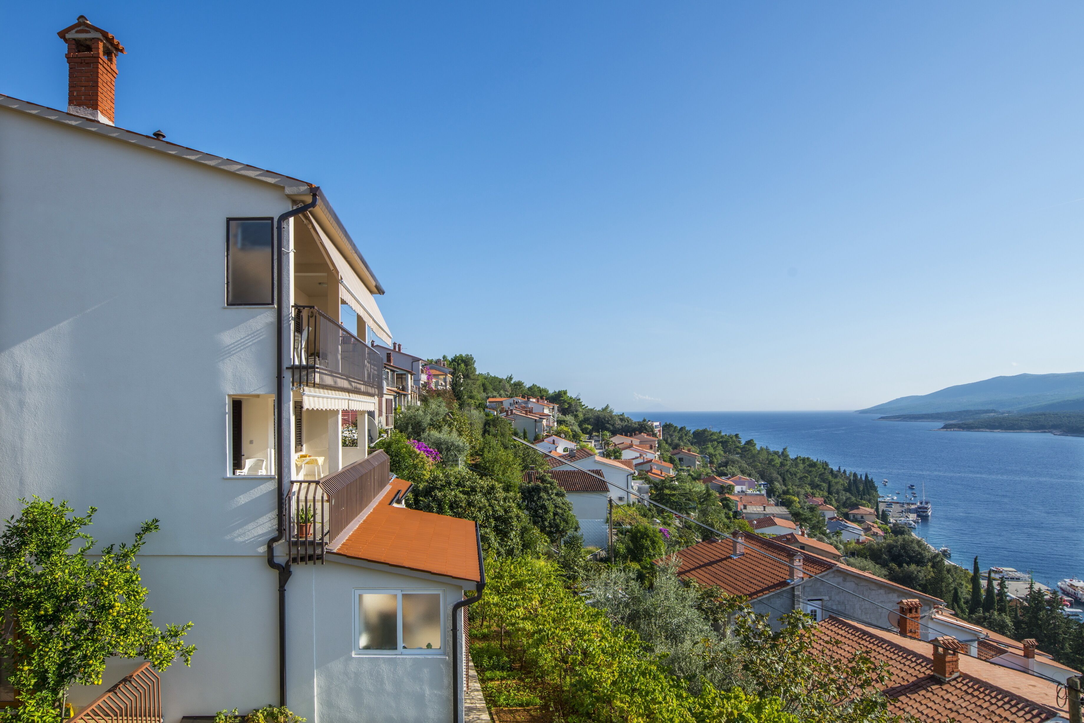Un quartier résidentiel situé sur la côte, avec des maisons à étages, des balcons et une vue sur la mer.