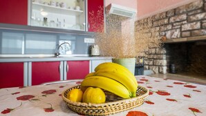 Eine Küche mit einem roten Schrank, einer Obstschale voller Bananen und Zitronen sowie einer Zierpflanze.