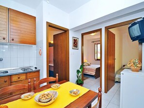Cozinha compacta com fogão a gás, armários de madeira e uma mesa de jantar posta com tigelas de comida.