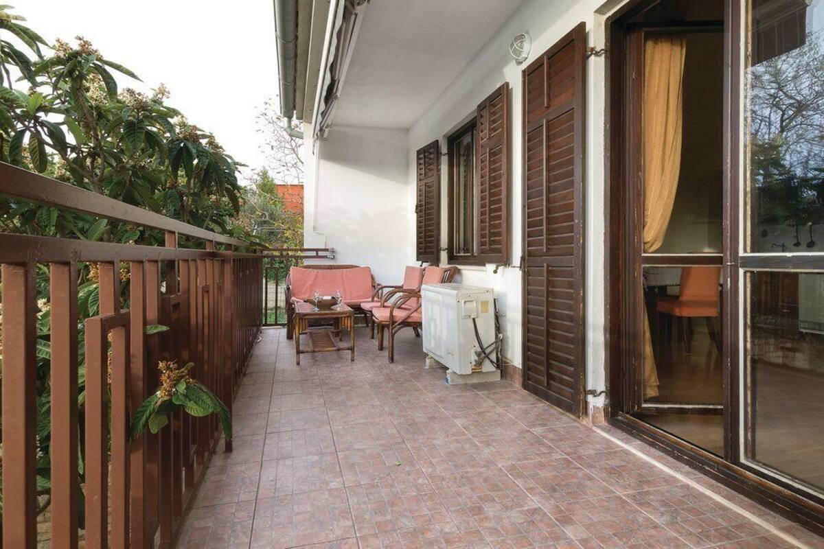 A balcony with a table and chairs, a radiator, and a window with curtains.