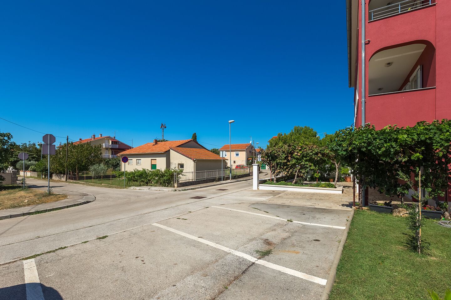 A quiet street with houses, a clear sky, and a red building.