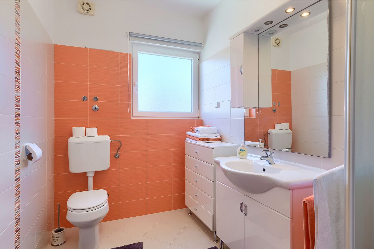 A bathroom with a toilet, sink, and mirror.
