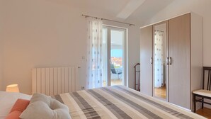 A bedroom with a bed, a radiator, a window with curtains, a chair, and a wardrobe. - Apartment Boris 771 (Fazana)