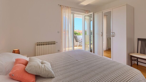A bedroom with a bed, a radiator, a chair, and a view of the outside. - Apartment Boris 771 (Fazana)