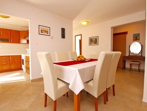 A dining area with a table set for four, surrounded by chairs, and a kitchen area with wooden cabinets and appliances.