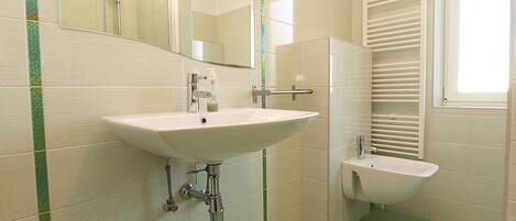Een badkamer met een grote spiegel, een wastafel en een hygiëneschuimer.