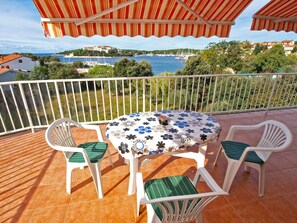 Un balcon avec une table ronde et quatre chaises, donnant sur une marina et une ville côtière.