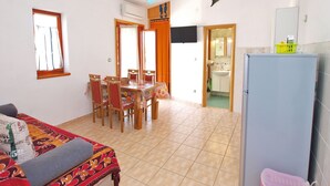Una habitación con una mesa de comedor, sillas, una cama, un refrigerador y una decoración de delfín en la pared.