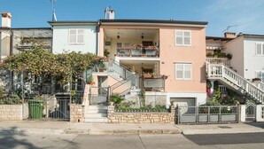 A two-story residential building with a balcony on the upper floor, a staircase leading to the entrance, and a small garden area in front. - Apartment Lucio 804 (Porec)