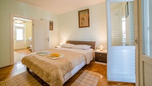 A bedroom with a bed, bedside tables, a nightstand, a door, and a window. - Apartment Lucio 804 (Porec)
