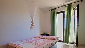 A bedroom with a bed, a nightstand, a lamp, a window with curtains, and a door. - Apartment Hasima 116 (Medulin)