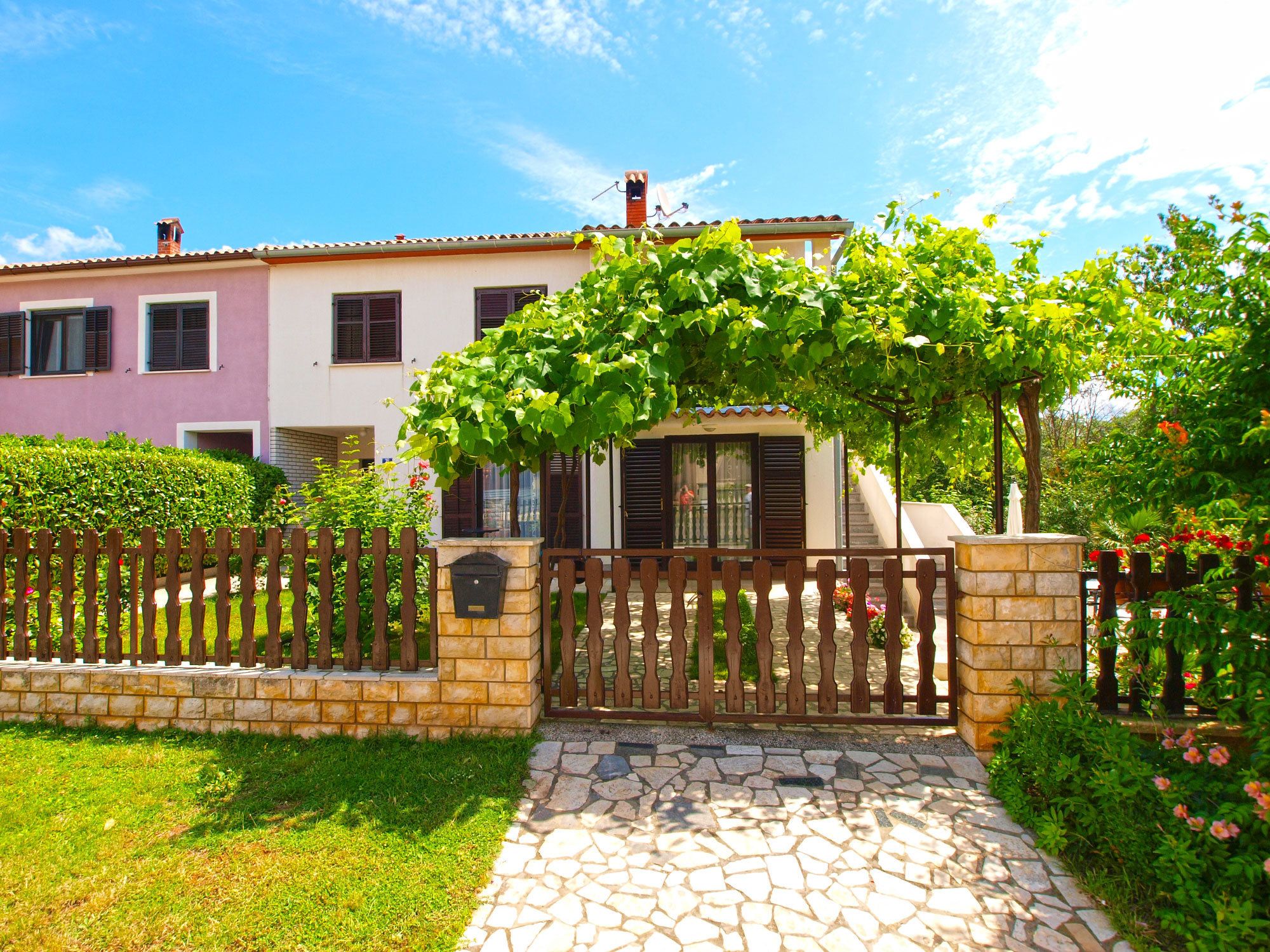 A two-story house with a stone pathway leading to a gated entrance.