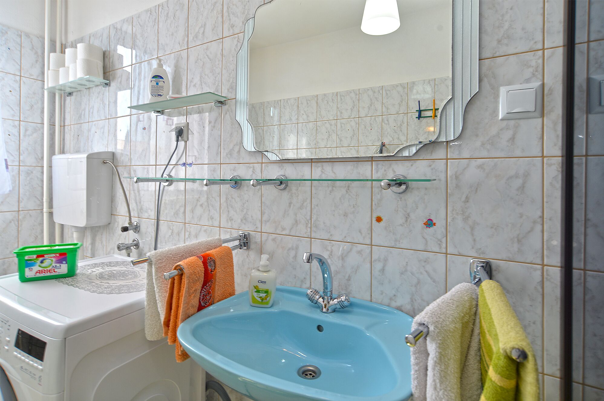 A bathroom with a blue sink, a mirror, and a towel rack.