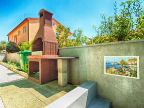 Uma casa com chaminé, um cesto de lixo verde e um quadro fixado na parede.