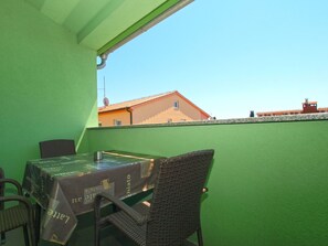 Ein Balkon mit Tisch und Stühlen, Blick auf Gebäude und eine grüne Wand.