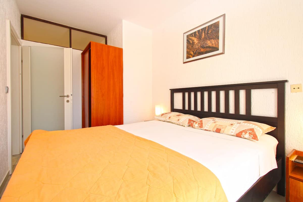A bedroom with a bed, a wardrobe, and a painting on the wall.