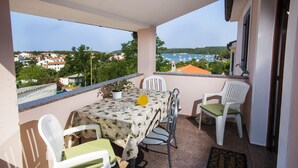 Un balcon avec une table dressée pour deux personnes, des chaises et une vue sur un port de plaisance et des immeubles.