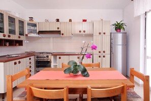 Ett modernt kök med träskåp, en gasspis, en ugn, ett kylskåp och ett matbord med stolar.
