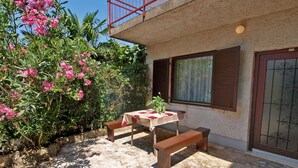 A patio with a table and benches, surrounded by lush greenery and pink flowers. - Apartments Celine 606 (Medulin)