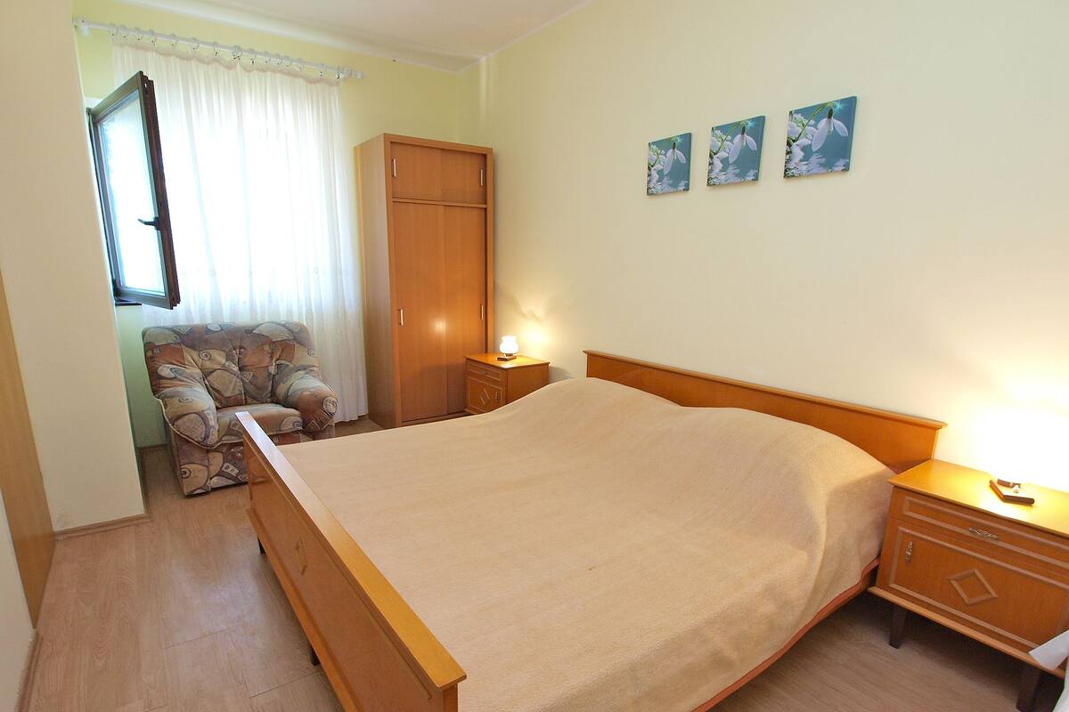 Une chambre à coucher comprenant un lit, une armoire, une chaise et une table de chevet.