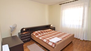 A bedroom with a bed, bedside table, lamp, and a window with curtains. - Apartments Celine 606 (Medulin)