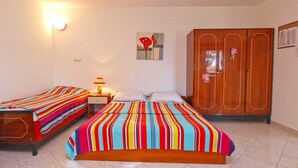 Un dormitorio con dos camas individuales, un armario de madera, una mesita de noche con lámpara y un aplique de pared.