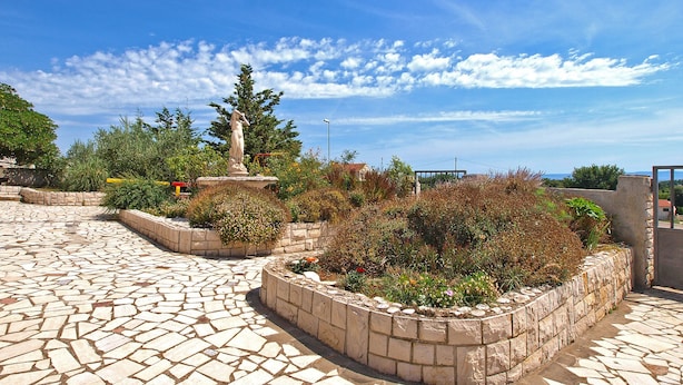 Un patio con piso de mosaico, una estatua y un muro de piedra con plantas.