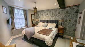 A neatly arranged bedroom with a large bed, bedside lamps, a window with curtains, and a wall-mounted clock. - Crown and Trumpet Inn (Broadway)