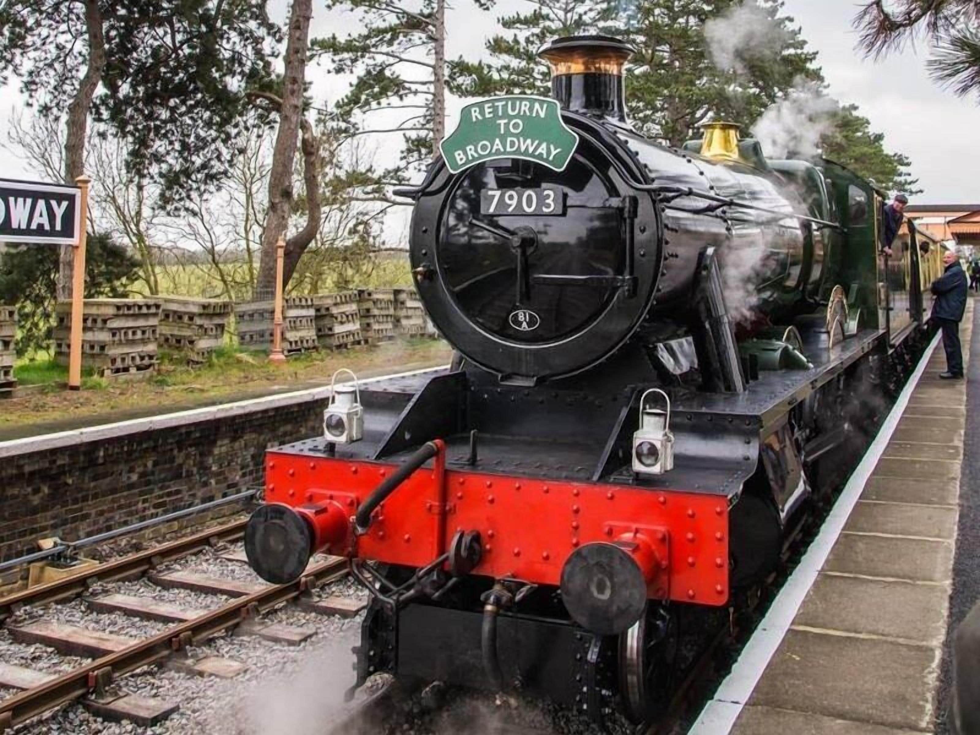 A steam locomotive with a 'RETURN TO BROADWAY' sign, number 7903, on a railway track.