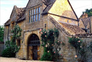 Un bâtiment historique en pierre, doté d’une grande entrée en arc de cercle, de nombreuses fenêtres et d’un toit à forte pente.