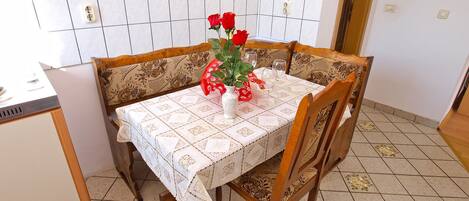 A dining table with a lace tablecloth, surrounded by wooden chairs with floral upholstery.