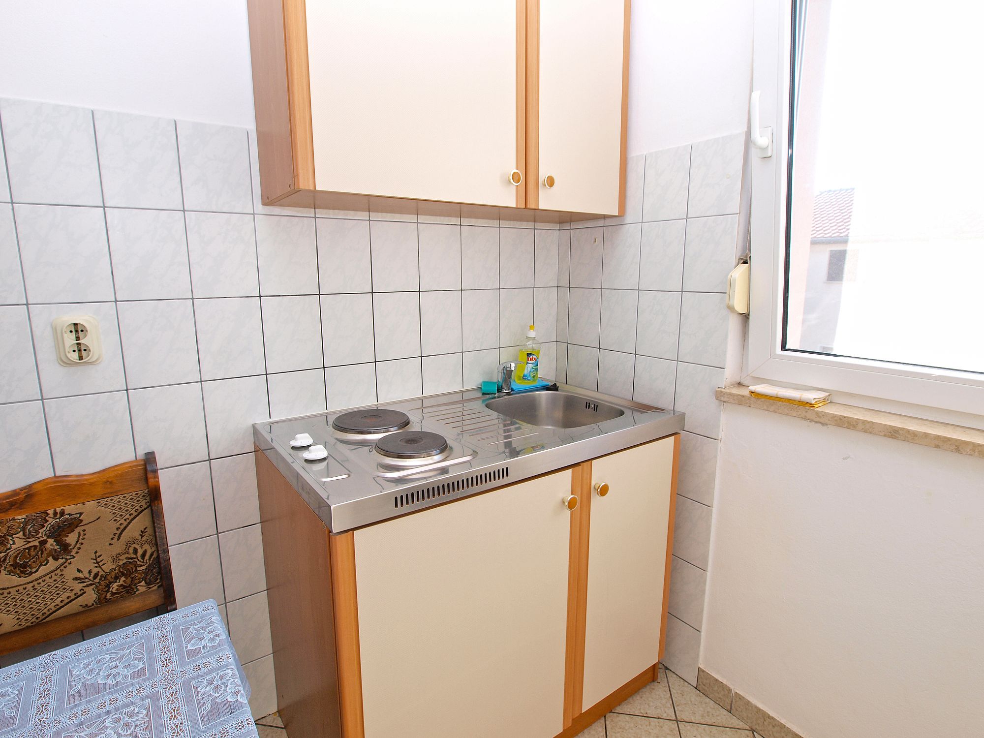Une petite cuisine équipée d’une cuisinière à gaz, d’un évier et de meubles de rangement en bois.