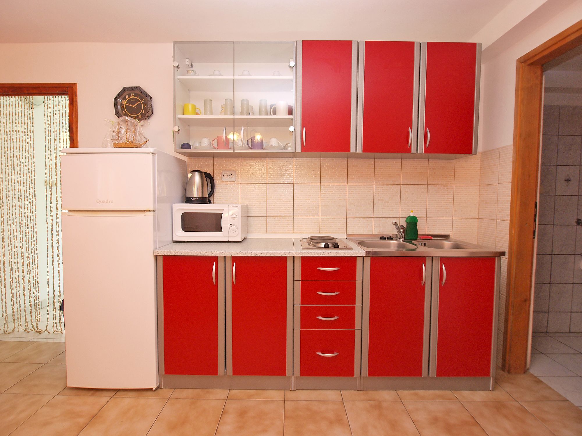 A kitchen with red cabinets, a white refrigerator, and a microwave.