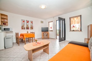 A compact living space with a dining area, a sofa, a TV, and a kitchenette.