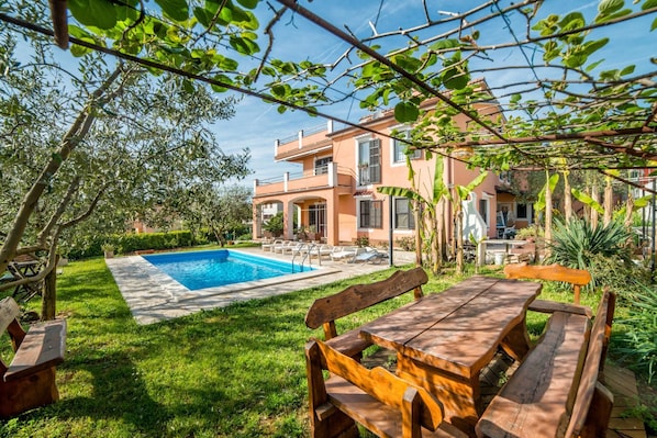 A poolside area with a wooden bench and a pool.