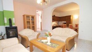 A living room with two sofas, a wooden coffee table, and a fireplace. There is a kitchen visible through an archway. - Apartments Ivan 65 (Pula)