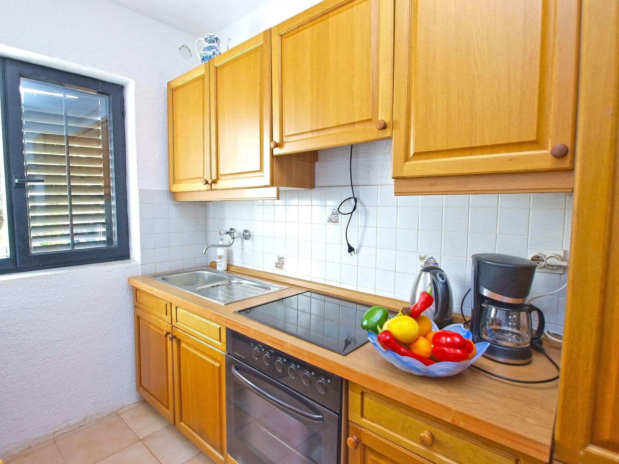 A kitchen with wooden cabinets, a stainless steel sink, a built-in oven, and a coffee maker.