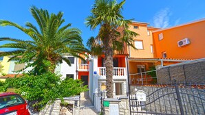 A residential street with a red car parked on the left, a stone wall, and a metal gate. - Apartments Ivan 65 (Pula)