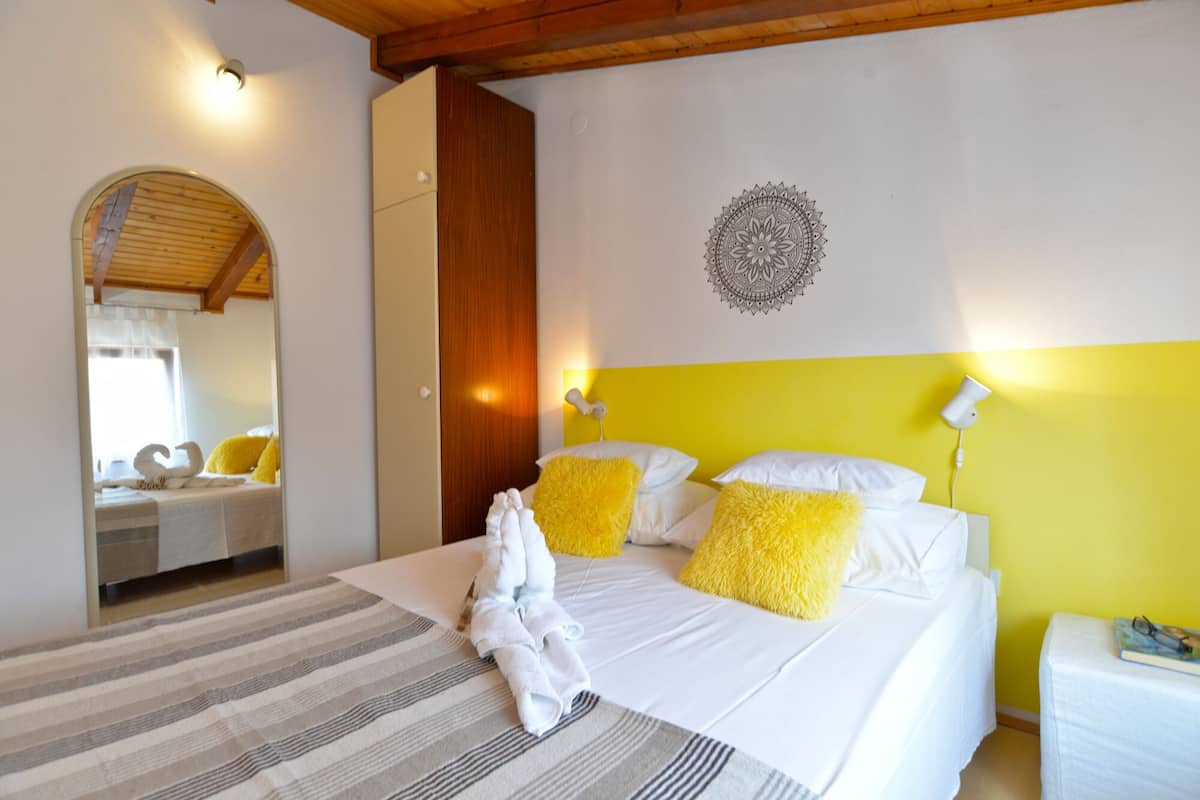 Ein Hotelzimmer mit Bett, Spiegel und Wandgestaltung mit einem Mandalamotiv sowie einer gelben Akzentwand.