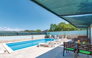 Une piscine avec des chaises longues et un espace patio couvert.