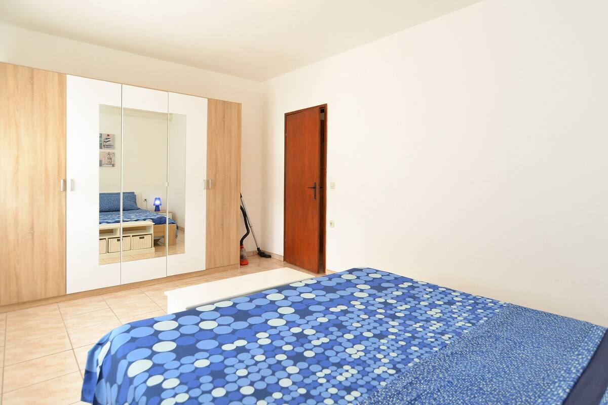 Un dormitorio con cama, armario, espejo y puerta.