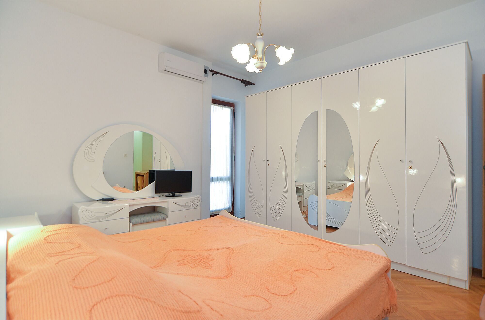 Une chambre à coucher comprenant un lit, une commode, un téléviseur, une armoire et un miroir.