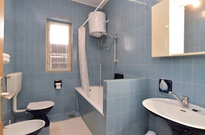 A bathroom with a toilet, bidet, bathtub, and sink.