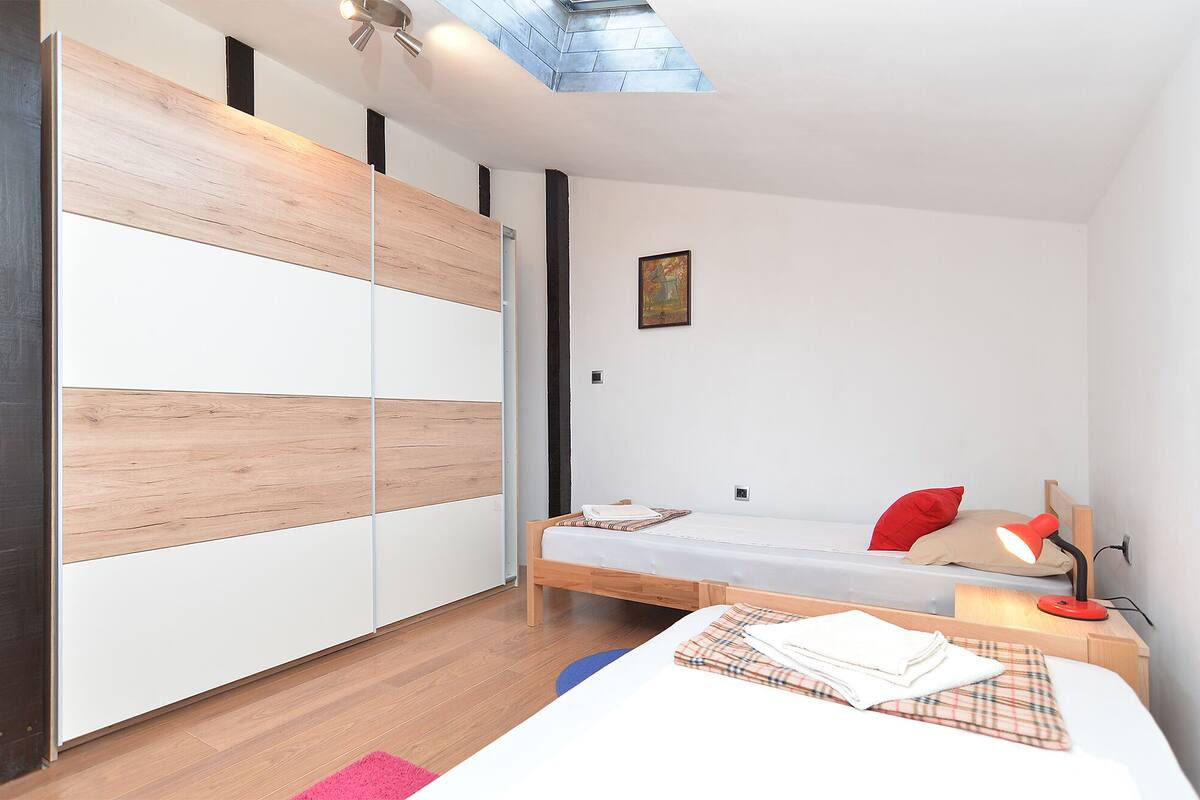 A modern bedroom with a bed, bedside table, lamp, and a painting on the wall.