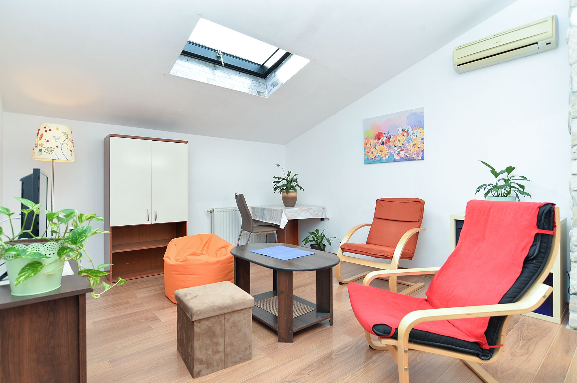 Un salon moderne avec une verrière, un coin repas et un fauteuil rouge.