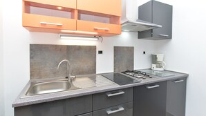 A modern kitchen with a stainless steel sink, a gas stove, and a coffee maker. - Apartments Mira 295 (Pula)